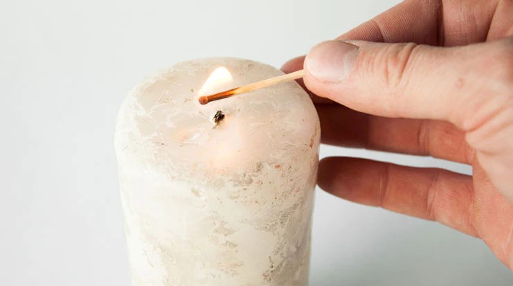 Use the lighter/match to light the candle.